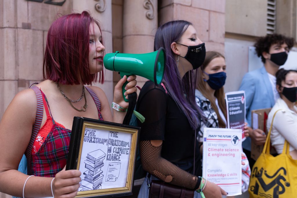 Photo of three young people protesting with signs and a megaphone