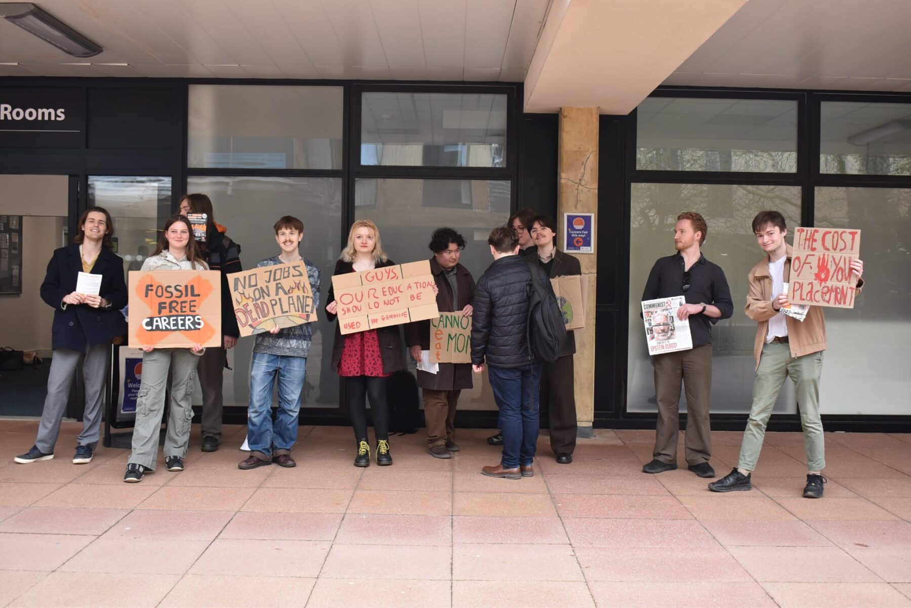 A group of students holding up placards outside a building